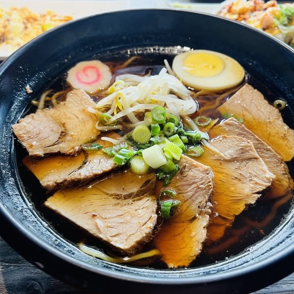 Chopstix ramen with sliced pork, bean sprouts, green onions, a soft-boiled egg, and narutomaki.